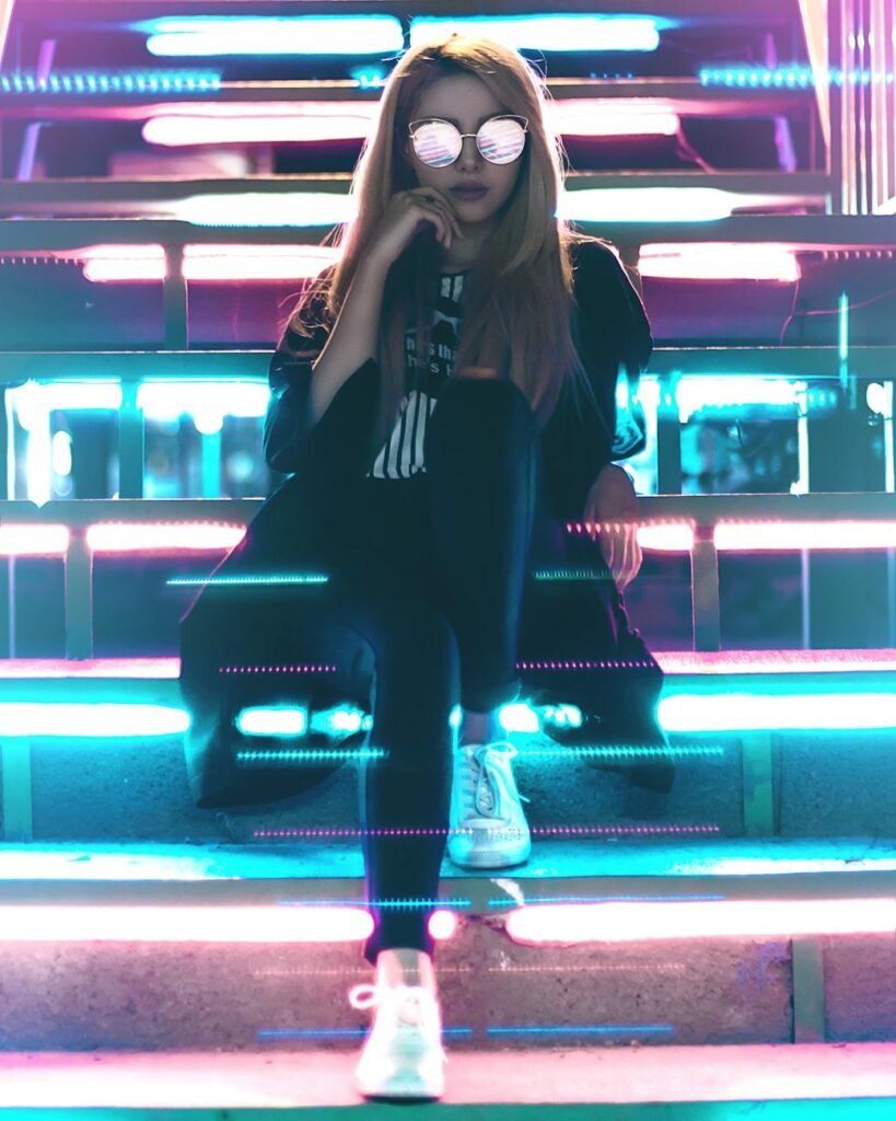 woman wearing black and sunglasses sitting near led lights