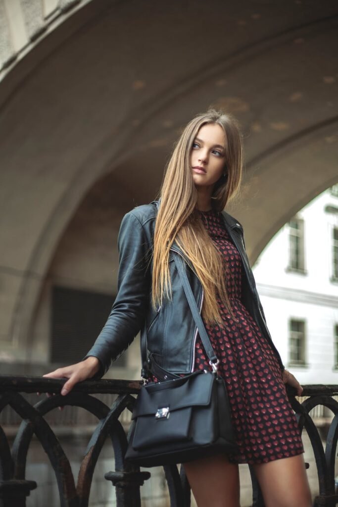 woman wearing black full zip leather jacket leaning on black metal fence